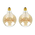 G125 E27 LED filament bulb with Love script filament, amber glass, lit, two bulbs on a white background
