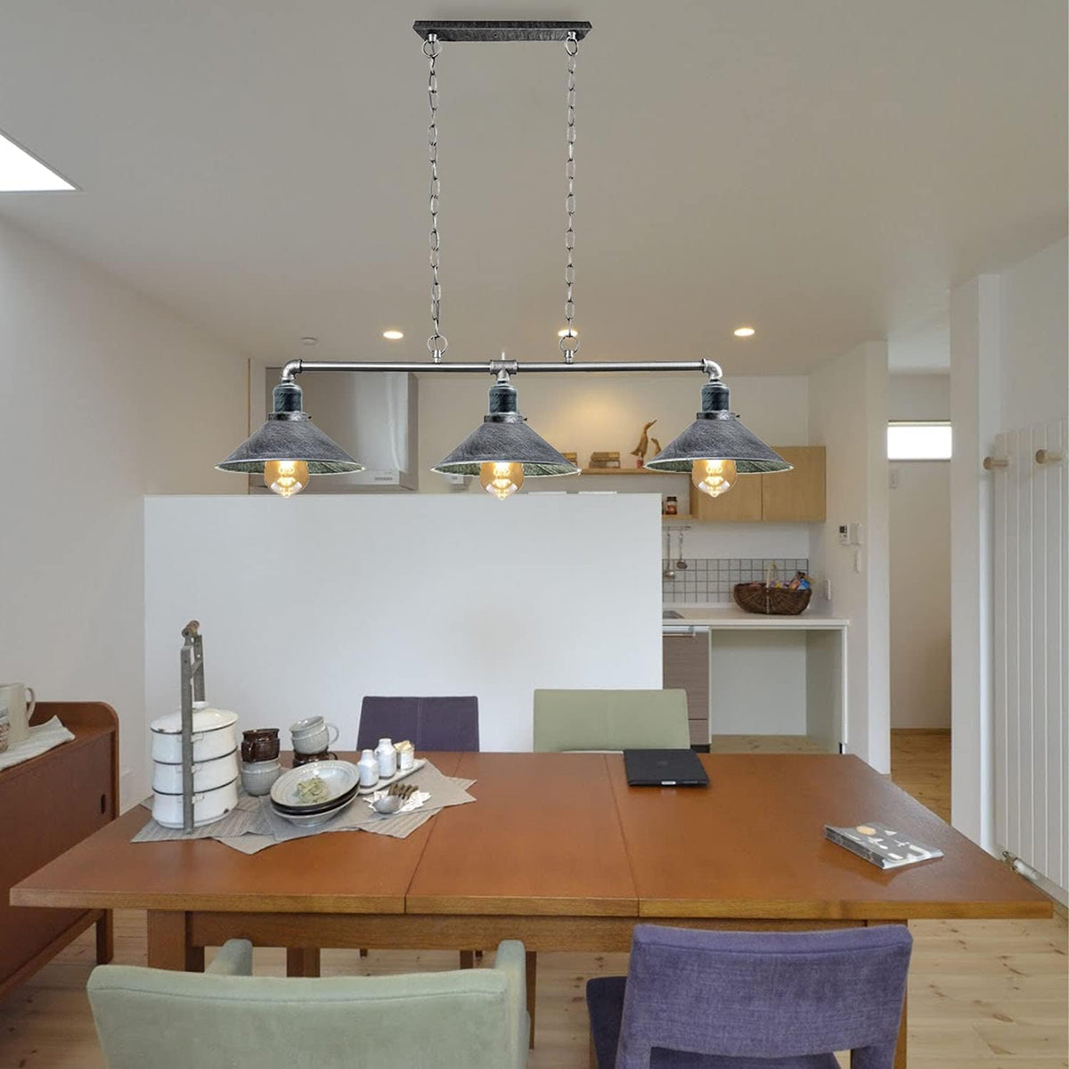 A steampunk ceiling light with three lit bulbs in textured metal shades, hanging above a dining table.