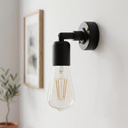 A modern black wall-mounted sconce with a clear glass Edison-style bulb