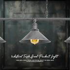 A steampunk ceiling light with three lit bulbs in gray conical shades, installed above a dining table.