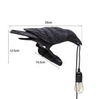 A black raven lamp with a lit bulb is shown with dimensions of 39cm wide, 12.5cm high, and 14.5cm deep.