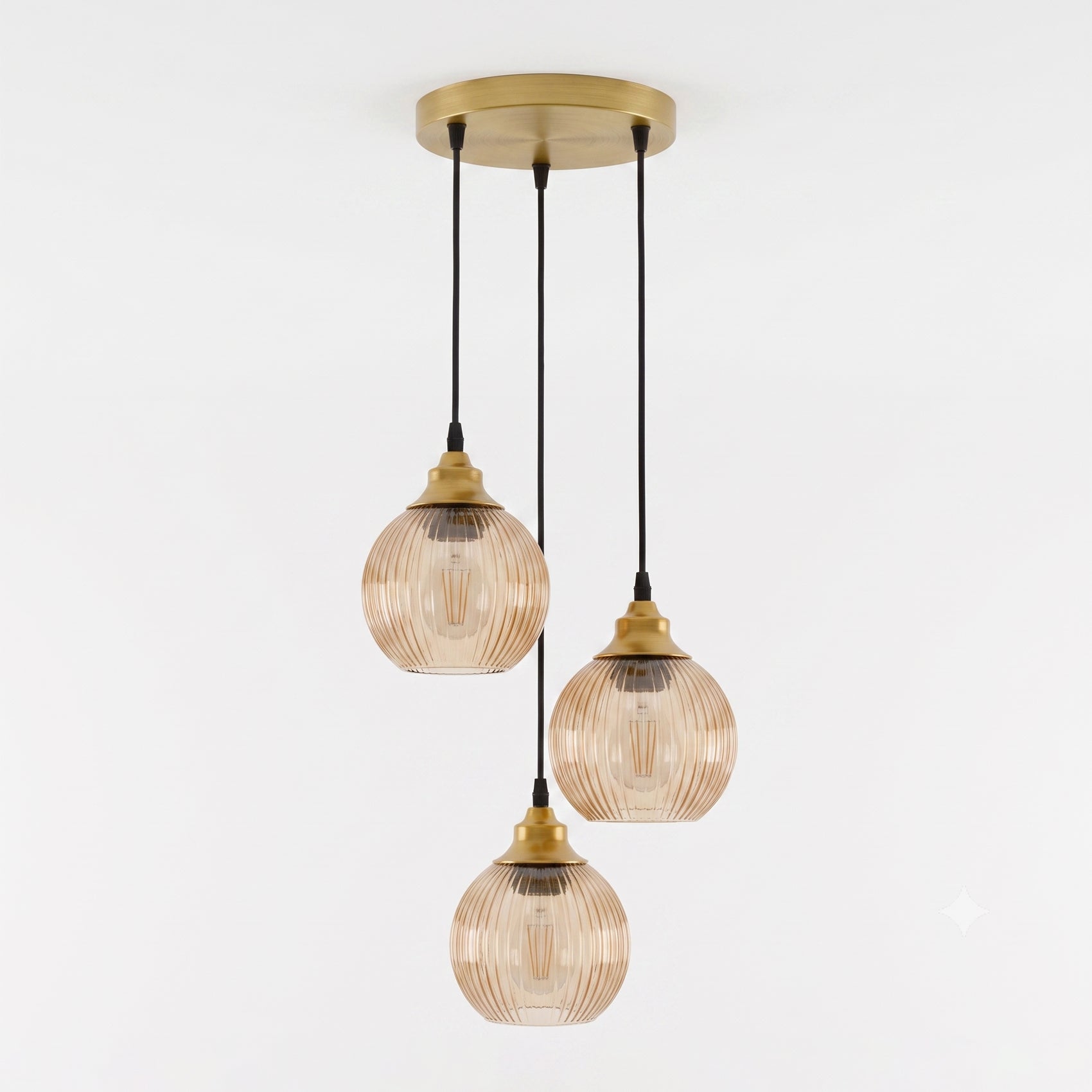 Three-light pendant ceiling fixture with ribbed amber-tinted glass shades and brass-toned metal hardware, suspended from a round ceiling canopy against a plain white wall.