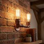 Decorative wall light fixture made from rusted metal pipes on a brick wall.