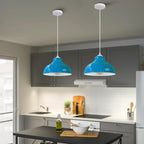 Two blue metal lamp shades with white interiors, suspended by white cords in a kitchen, unlit.