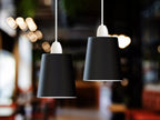 Two modern black pendant lights with white sockets hanging from white cords in a softly blurred indoor setting.
