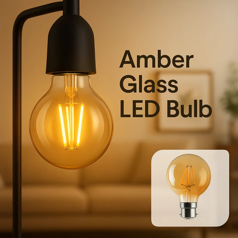 An amber glass LED light bulb with a visible filament, shown illuminated on a black lamp fixture against a warm indoor background.